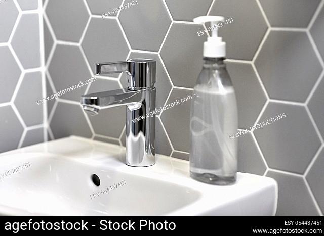 close up of water tap with liquid soap on sink