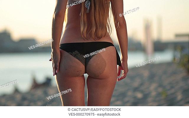 Sexy sandy woman buttocks in bikini on the beach