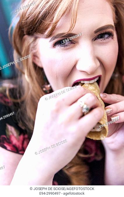 A smiling 27 year old redheaded woman eating a taco