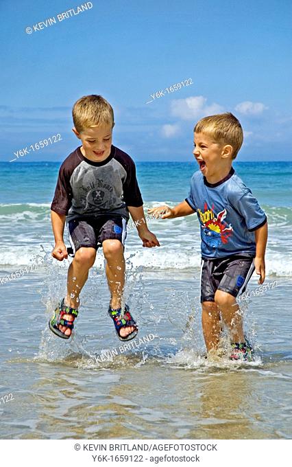 two little boys splashing in the sea in cornwall, uk