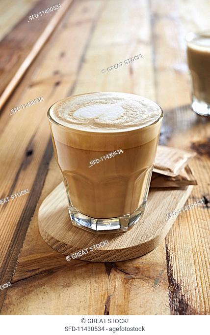 A glass of cappuccino decorated with a milk heart