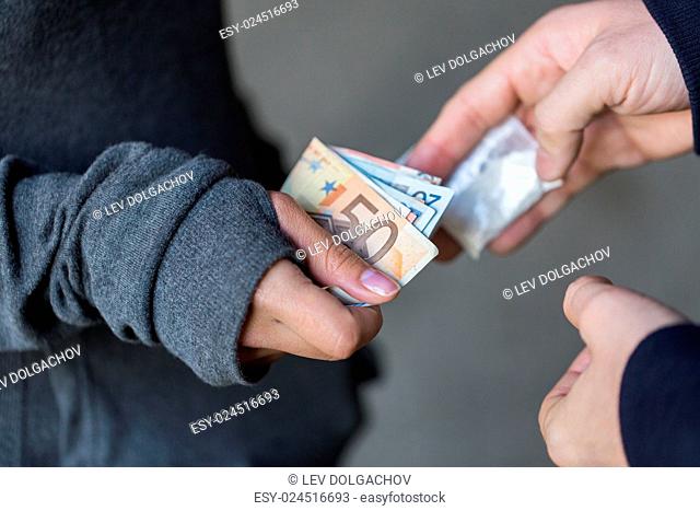 drug trafficking, crime, addiction and sale concept - close up of addict with money buying dose from dealer on street