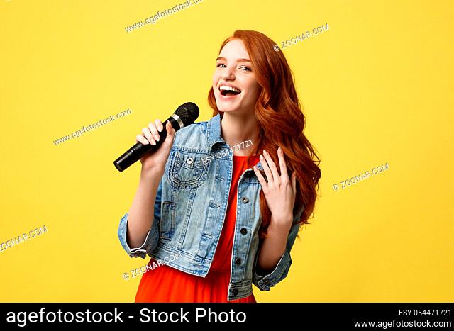 Lifestyle and People Concept: Expressive beauty ginger hair model girl in casual jean cloth singer with a microphone