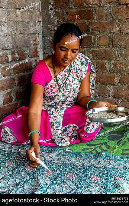 Adivasi woman sticking beads onto a sari in a village in Narmada district, Gujarat, India, Asia