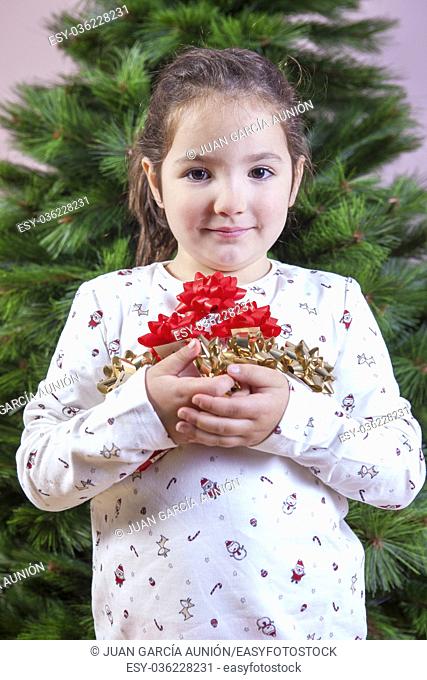 Merry Christmas and Happy New Year. Smiling little girl with a lot of ribbons for Christmas tree decoration. She is very, very happy