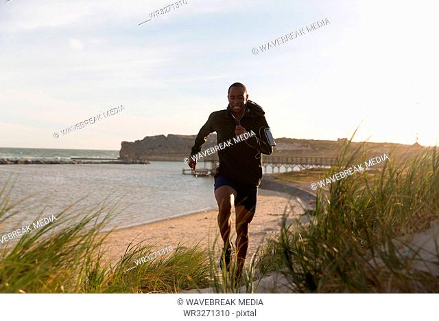 Male athlete jogging near beach