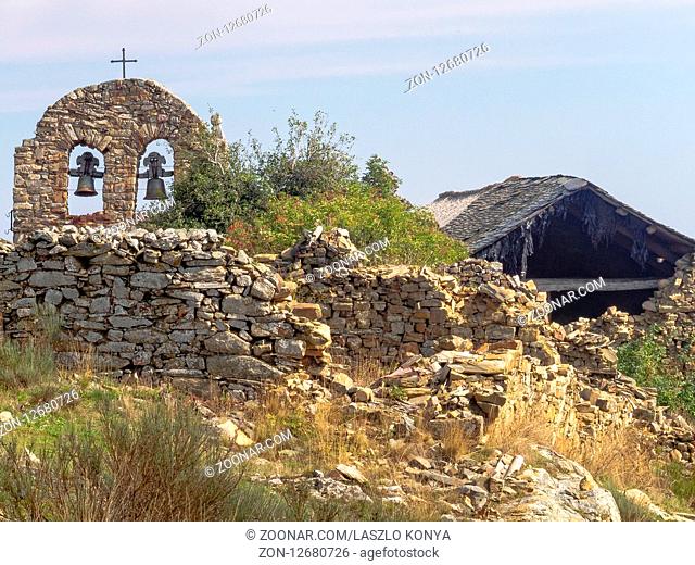 Bell gable among crumbling houses in a semi-abandoned village - Foncebadon, Castile and Leon, Spain