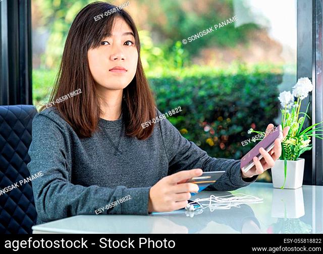 Young woman sitting sholding passport and credit card in home office