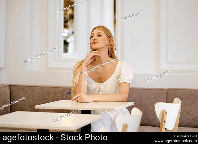 Young pensive woman waiting for her order in a cafe
