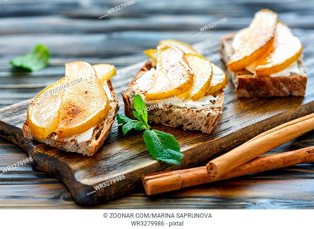 Crostini with ricotta and pear on a wooden stand, selective focus
