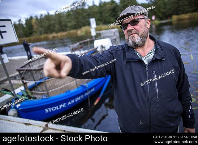 PRODUCTION - 26 October 2023, Mecklenburg-Western Pomerania, Stolpe: Ferryman Ulf Radicke stands at the pier of the small passenger ferry across the Peene and...