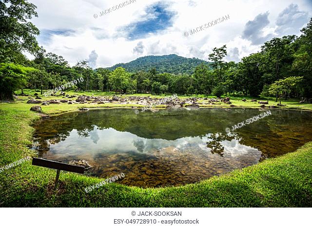 Crystalline hot spring pond reflect cloudy sky inside forest area of Chae Son national park, Lampang province of Thailand
