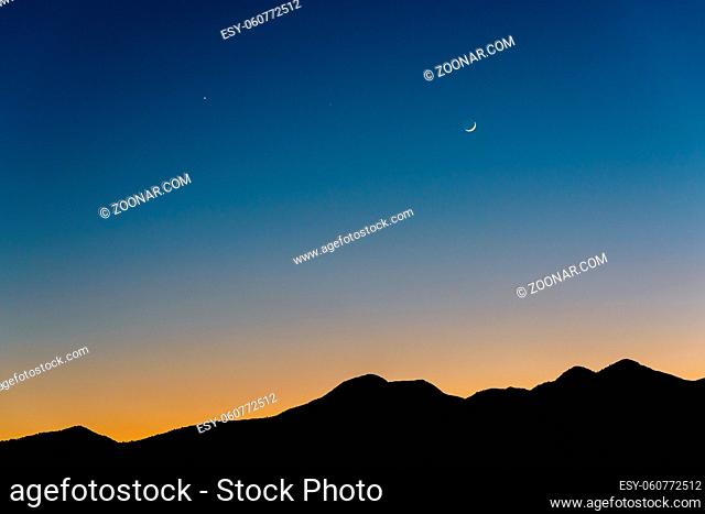 Waxing crescent Moon, Venus (left) and Saturn (middle) at dusk. Silhouette of mountains near Kathmandu in Nepal