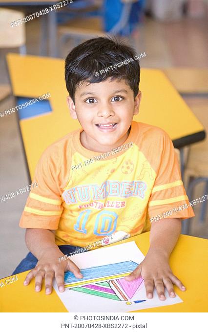 Portrait of a schoolboy sitting in a classroom and smiling