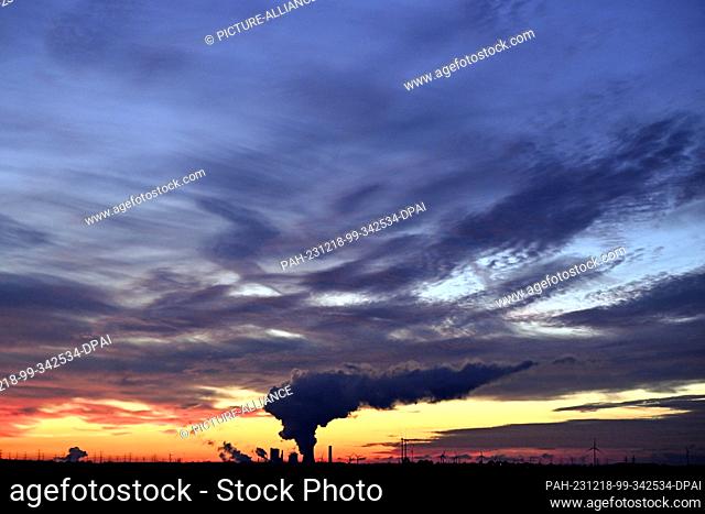 18 December 2023, North Rhine-Westphalia, Niederaußem: The sun sets behind the Niederaussem lignite-fired power plant. While the weather in the south of North...