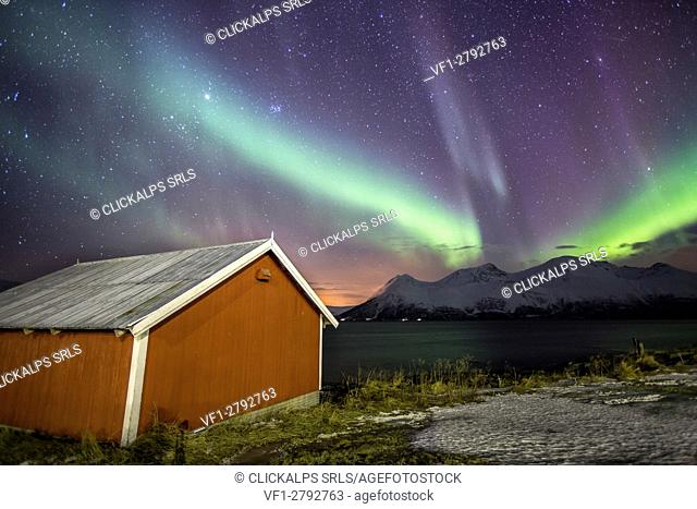 Northern Lights illuminates the wooden cabin at Svensby Lyngen Alps Tromsø Lapland Norway Europe