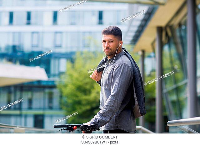 Man with headphones carrying jacket over shoulder looking at camera