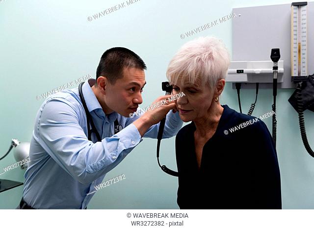 Young Asian male doctor examining a senior patient in the clinic
