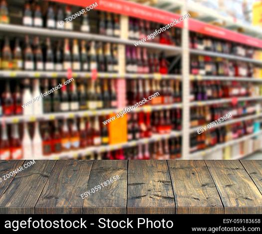 Vintage wooden boards with view to shelves of supermarket. Table top with shopping place. Vintage boards with alcoholic drinks on shelves of shop