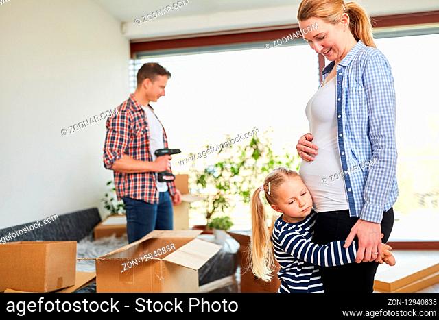 Mädchen umarmt ihre schwangere Mutter beim Umzug mit vielen Umzugskartons