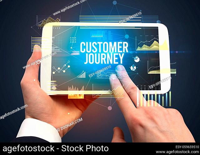 Close-up of hands holding tablet with CUSTOMER JOURNEY inscription, modern business concept