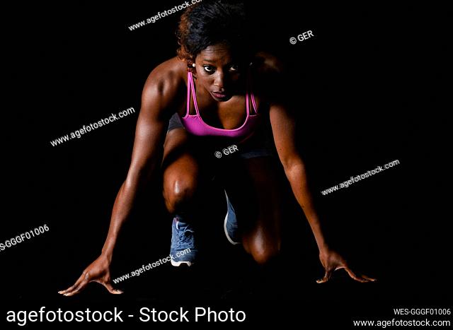 Athlete in starting position for running against black background