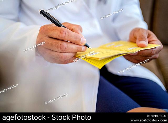 Close-up of doctor writing in vaccination pass