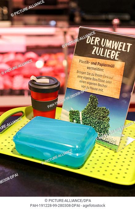 15 November 2019, Saxony, Leipzig: A sign ""For the sake of the environment"" is placed next to a plastic box and a reusable coffee cup on a tray in a...