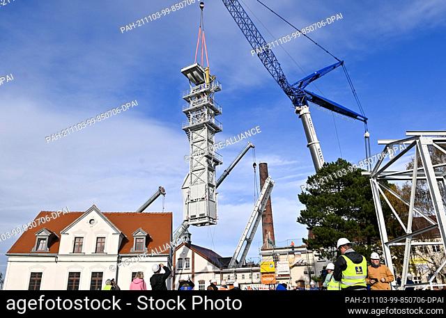 03 November 2021, Saxony, Freiberg: A crane is used to lift the guide frame for the winding tower at the Reiche Zeche research and training mine of the TU...