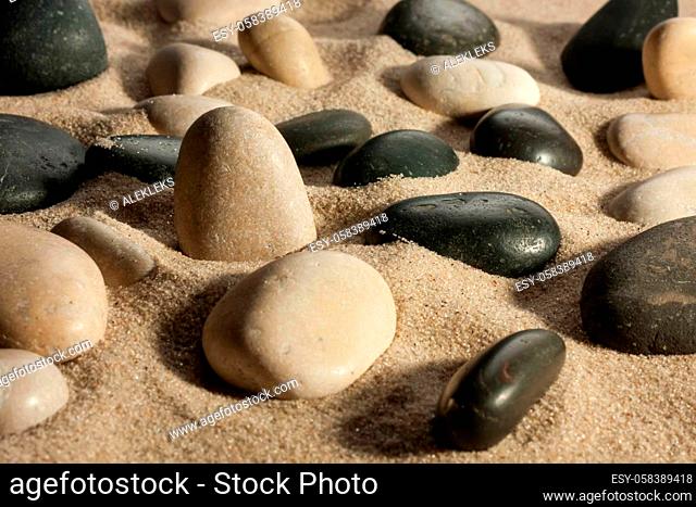 Close up of stones sticking out of the sand in the sunlight, as a background
