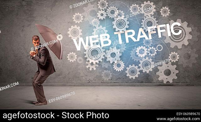 Businessman defending with umbrella from WEB TRAFFIC inscription, technology concept