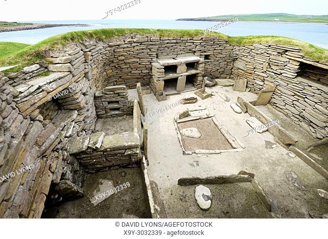 Skara Brae Stone Age Neolithic village at Skaill, Orkney, Scotland. Interior, box beds, hearth and dresser 3100 BC. House 1 with Bay of Skaill behind