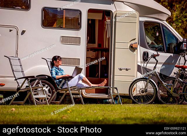Woman looking at the laptop near the camping . Caravan car Vacation. Family vacation travel, holiday trip in motorhome RV