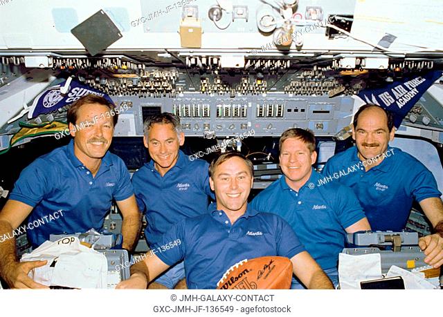 The crew members for the STS-27 space flight pose on the flight deck of the Earth-orbiting space shuttle Atlantis with a football free-floating in the...