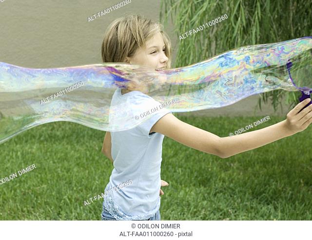 Girl making long bubble with bubble wand
