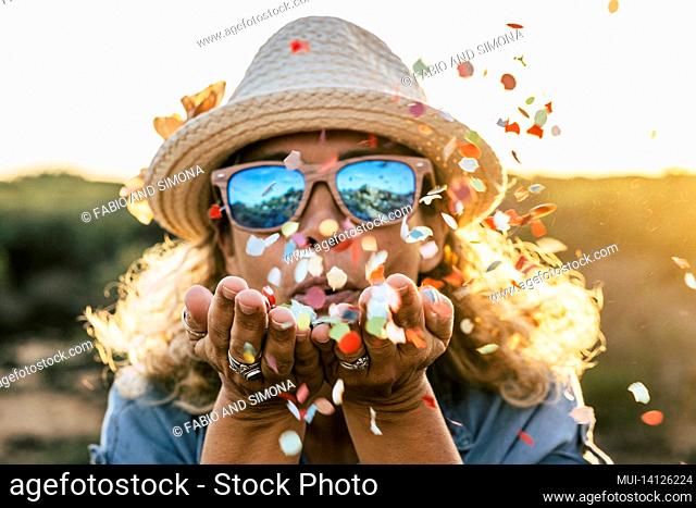 beautiful defocused woman blow confetti from hands. celebration and event concept. happiness and colored image. movement and happiness for active people...