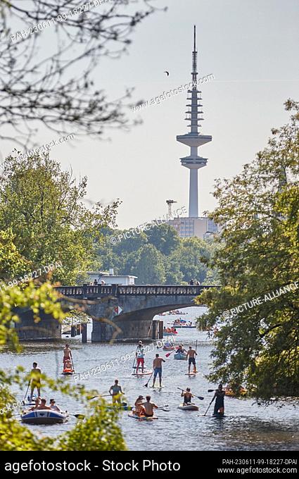 11 June 2023, Hamburg-Winterhude: Stand-up paddlers and rowers enjoy their trip on a canal of the Außenalster in Hamburg-Winterhude on Sunday in summery warm...