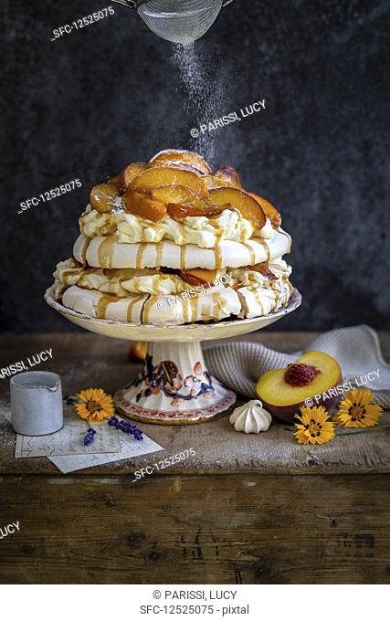 Pavlova with peaches, caramel sauce and powdered sugar
