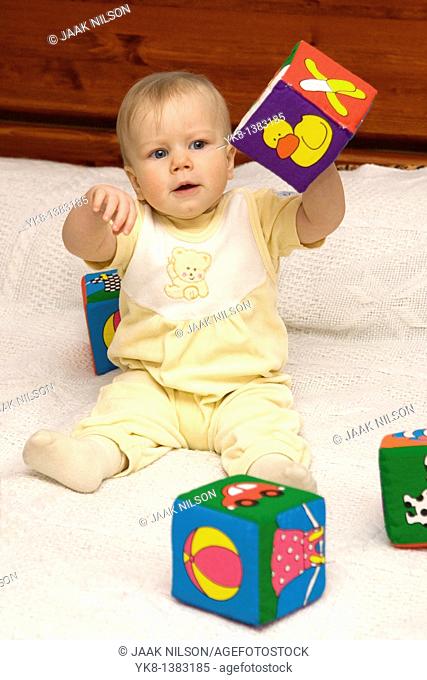 Happy Eight Month Old Infant Girl Playing With Cubes on Bed