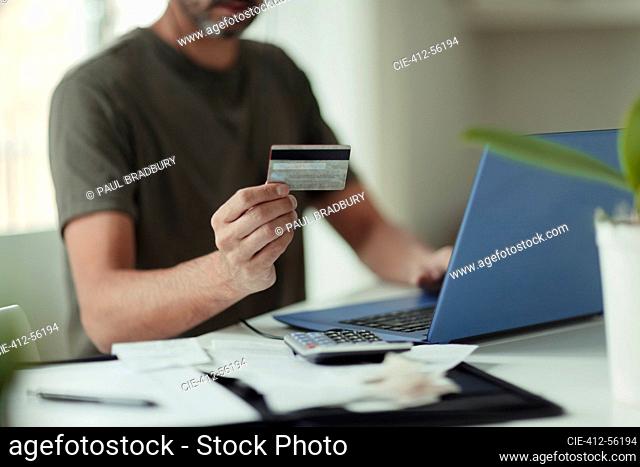 Man with credit card online shopping at laptop