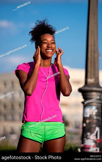 portrait of a young African American girl with headphones to run beautiful summer morning on city streets