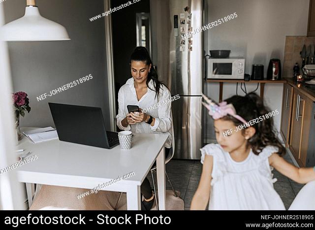 Woman using cell phone in kitchen