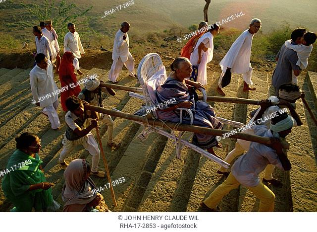 Jain pilgrims walking and being carried up the sacred hill of Palitana, Gujarat state, India, Asia