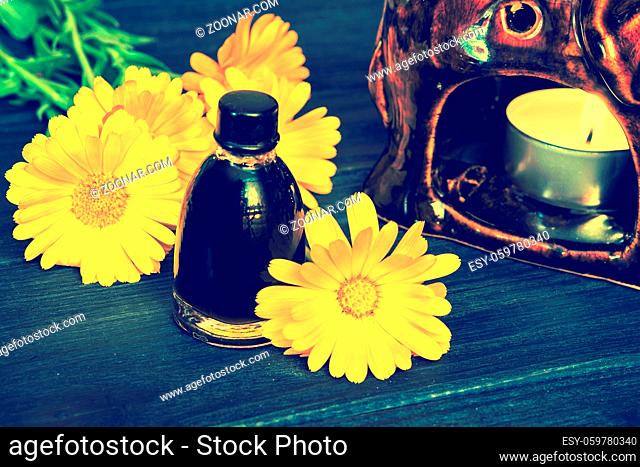 Calendula oil in a glass bottle on an wooden background. Vintage dark toned effect