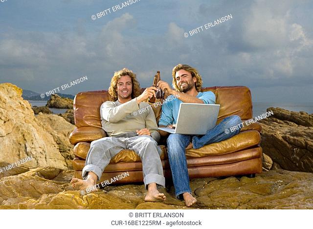 young men with laptop and beer, couch at