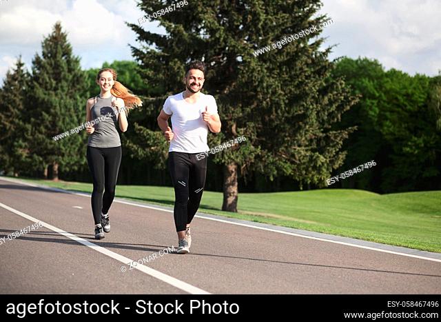 Fitness, sport, friendship and lifestyle concept - smiling couple running outdoors. Man and woman training after hard-working day