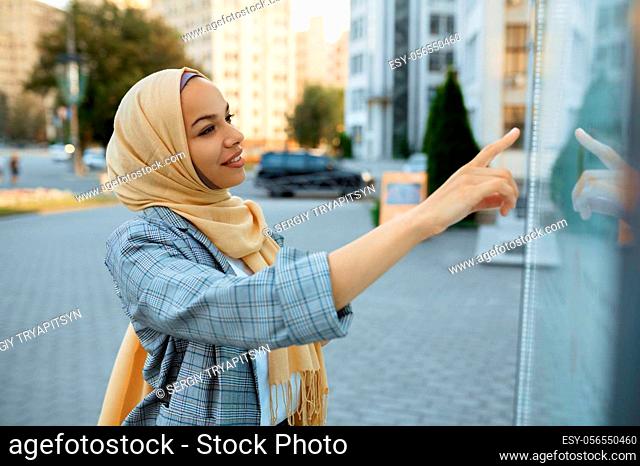 Arab female student in hijab looking on map in downtown. Muslim woman at the entrance to the business center. Religion and education