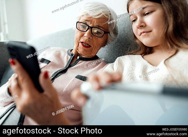 Woman showing mobile phone with girl at home