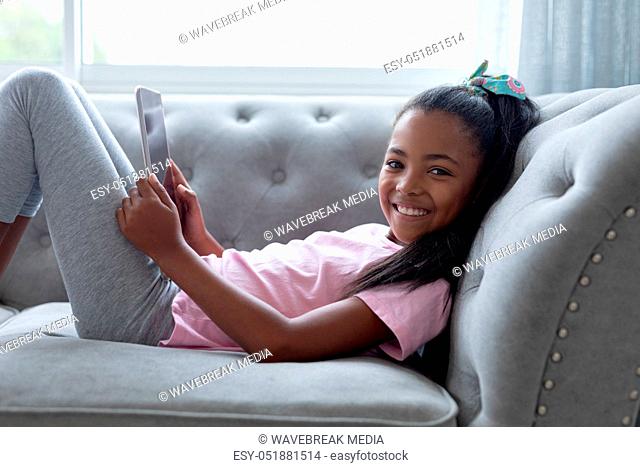 Girl using digital tablet on a sofa in living room