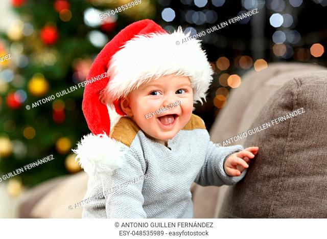 Joyful baby looking at camera in christmas on a couch in the living room at home